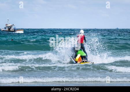 Un sauveteur de la RNLI Royal National Lifeboat institution patrouillant au large de Towan Beach en jet ski sur la côte de Newquay en Cornouailles au Royaume-Uni. Banque D'Images