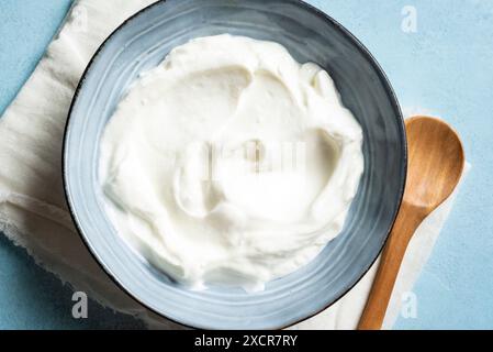 Yaourt grec fait maison dans un bol bleu gros plan, vue de dessus. Yaourt grec naturel biologique, fromage à la crème labneh, crème sure pour un petit déjeuner sain. Banque D'Images