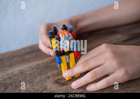 Gros plan des mains des enfants créant la construction à partir de pièces, figure de robot alpiniste, éducation de l'ingénierie, apprentissage par le jeu Banque D'Images