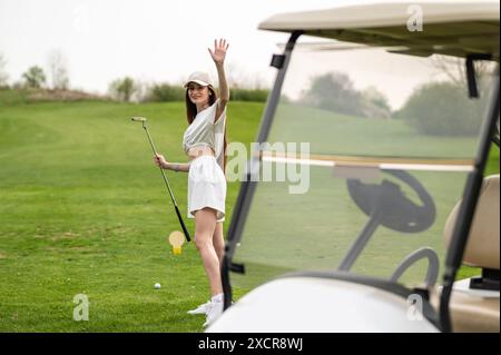 Fille mince portant jupe posant avec des équipements de golf sur la pelouse Banque D'Images