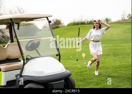 Femme active posant avec un équipement de golf près du véhicule à l'extérieur Banque D'Images