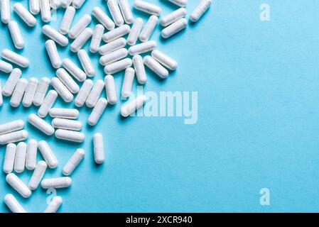Capsules médicales blanches sur fond bleu clair, espace de copie. Schéma de médicaments. Médecine, compléments alimentaires, pharmacie et concept de soins de santé. Banque D'Images