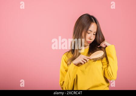 Jeune belle femme asiatique bouleversée avec un peigne et des cheveux à problème, Portrait femme choquée souffrance Banque D'Images