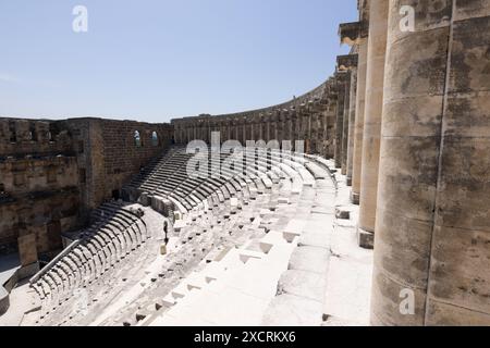 Les sièges en pierre escarpés au célèbre théâtre antique d'Aspendos près d'Antalya en Turquie par une journée ensoleillée avec le ciel bleu et les gens se promenant. Banque D'Images