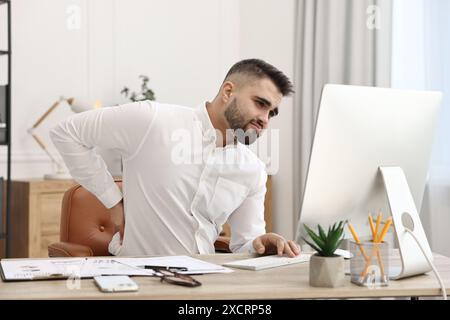 Homme souffrant de douleurs dorsales au bureau. Symptôme de mauvaise posture Banque D'Images