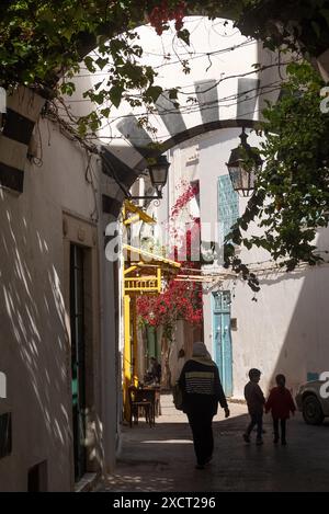 Une mère tunisienne et ses enfants marchent dans les belles rues étroites de la Médina de Tunis, la traditionnelle Kasbah est un site du patrimoine mondial et une destination touristique populaire en Tunisie. Banque D'Images