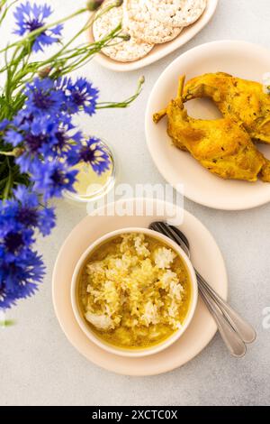 Ragoût de lapin avec du riz, du brocoli et des gâteaux de riz, une table servie avec de la nourriture et un vase de fleurs, un délicieux déjeuner copieux ou dîner Banque D'Images