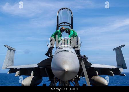 Mer des Philippines. 14 juin 2024. Des marins américains effectuent la maintenance d'un F/A-18F Super Hornet, affecté au Black Knights of Strike Fighter Squadron (VFA) 154, sur le poste de pilotage à bord du porte-avions de classe Nimitz USS Theodore Roosevelt (CVN 71), le 14 juin 2024. Theodore Roosevelt, navire amiral du Carrier Strike Group Nine, mène des opérations de routine dans la zone d'opérations de la 7e flotte américaine. La 7e flotte américaine est la plus grande flotte numérotée déployée vers l'avant de l'US Navy, et interagit et opère régulièrement avec des alliés et des partenaires pour préserver une regio indo-pacifique libre et ouverte Banque D'Images