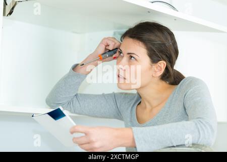 Femme avec des meubles à assembler soi-même dans la cuisine Banque D'Images