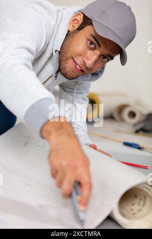 jeune homme faisant des réparations dans l'appartement tapisserie sur le mur Banque D'Images