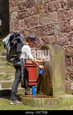 Pèlerin déposant une bouteille d'eau d'une fontaine dans la ville française de Saint-Jean-pied-de-Port au départ du chemin de pèlerinage du Camino de Santiago Banque D'Images