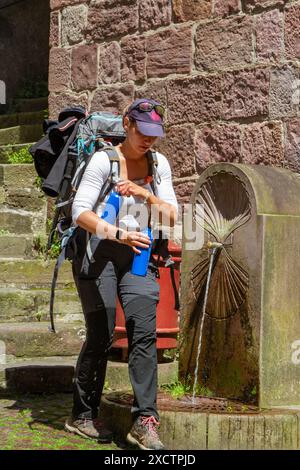 Pèlerin déposant une bouteille d'eau d'une fontaine dans la ville française de Saint-Jean-pied-de-Port au départ du chemin de pèlerinage du Camino de Santiago Banque D'Images