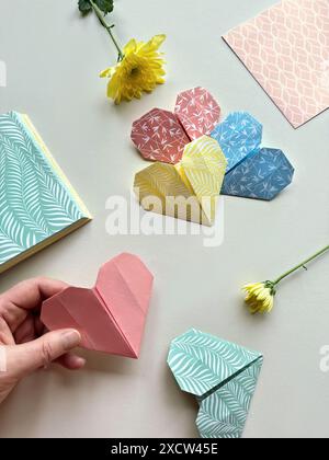 Fabrication artisanale de coeurs Origami colorés avec du papier à motifs et des fleurs fraîches Banque D'Images