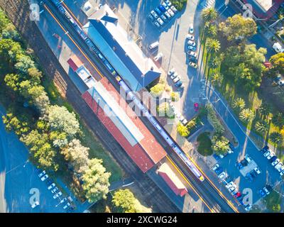 Vue aérienne voie ferrée et train en gare montrant les parkings, véhicules, bâtiments, routes et arbres, Castlemaine, Victoria, Australie. Banque D'Images
