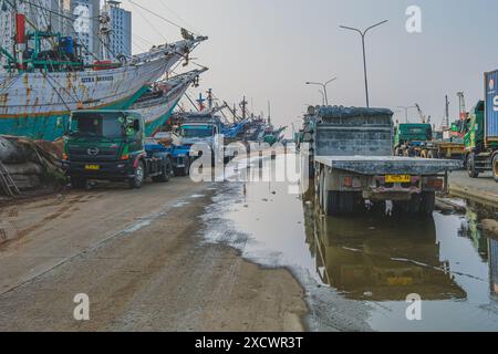 Jakarta Indonésie - 9 mai 2024. Une rangée de semi-camions colorés stationnés à côté d'une rangée de navires traditionnels indonésiens amarrés appelés Phinisi. Banque D'Images