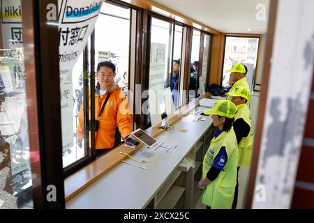 19 juin 2024, district de Minamitsuru, Yamanashi, Japon : Kotaro Nagasaki gouverneur de Yamanashi scanne son code QR de réservation au 5e centre d'administration de la ligne Fuji Subaru, le point de départ le plus populaire pour gravir le mont Fuji. Le gouverneur Nagasaki a participé à une répétition en tant qu'alpiniste, montrant aux médias le fonctionnement actuel de la 5e station, y compris la collecte des droits d'entrée pour les grimpeurs. À partir de cette année, les autorités mettront en œuvre de nouvelles mesures telles qu’une limite de 4000 grimpeurs par jour, une augmentation des frais d’accès et un service à durée limitée. La saison de randonnée commence du 1er juillet à Septembe Banque D'Images