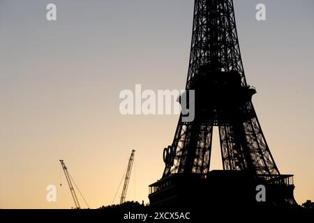Paris, France - 07 juin 2024 : silhouette de la tour Eiffel dans la lumière tôt le matin. Logo des jeux olympiques monté sur la tour et grue de construction au sol. Banque D'Images