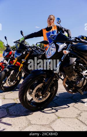 Une femme dans un gilet orange se tient à côté d'une rangée de motos Banque D'Images