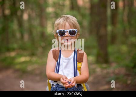 Enfant blond, mangeant des bleuets sauvages dans la forêt, les rassemblant lui-même Banque D'Images