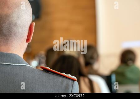 Bamberg, Allemagne. 17 juin 2024. Un soldat de la Bundeswehr est assis dans les rangs d'une classe scolaire. Les officiers de la jeunesse de la Bundeswehr viennent dans les écoles sur demande. En tant que conférenciers de l'éducation politique, ils fournissent des informations sur la politique de sécurité et l'importance des soldats. Crédit : Pia Bayer/dpa/Alamy Live News Banque D'Images