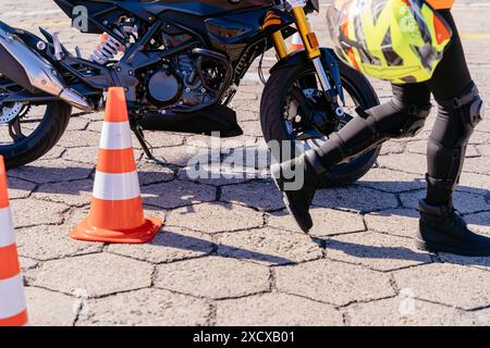 Une personne s'enfuit d'une moto arrêtée devant un cône Banque D'Images