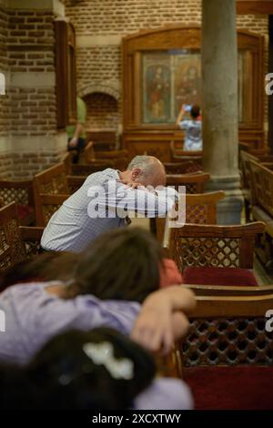 Les gens de différents âges prient dans une vieille église avec des murs de briques et des bancs en bois Banque D'Images