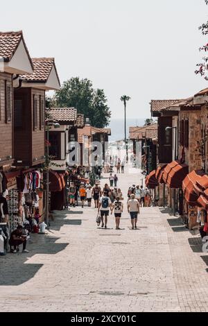 Les gens sur la rue principale marchant à la marina dans la ville historique de Side près d'Antalya en Turquie par une journée ensoleillée, avec des bâtiments traditionnels. Banque D'Images