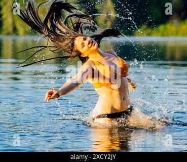Femme aux cheveux longs éclaboussant dans le lac Banque D'Images