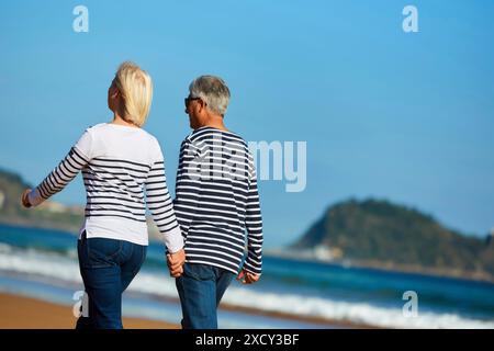 Couple senior, 60-70, marche sur la plage, fond Getaria, Zarautz, Gipuzkoa, pays Basque, Espagne, Europe Banque D'Images