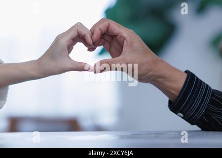 Les couples affichent des symboles en forme de cœur ensemble pour montrer leur amour et leur amitié les uns pour les autres sur leur grand jour. fabrication du symbole de coeur en forme de main à ex Banque D'Images