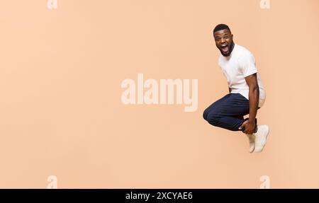 Homme excité sautant contre le fond de Peach Studio Banque D'Images