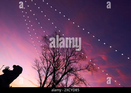 Crépuscule incroyable avec un ciel serein plein de nuages violets balayants et guirlandes guidées. Il y a une petite statue de sirène illuminée avec rétro-éclairage contempler Banque D'Images