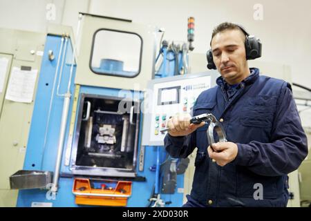 Travailleur mesurant avec pied à coulisse. ECROU de blocage. Usinage par transfert. Indecober usiné. Usinage de pièces de précision en série. Industrie automobile. Berri Banque D'Images