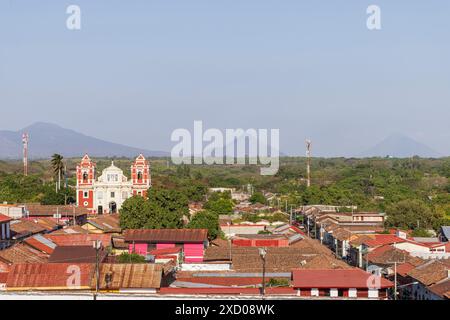 Vue panoramique depuis le toit de la cathédrale blanche de la ville coloniale Leon au Nicaragua en Amérique centrale. Regardant l'église du Calvaire doux nom de Jésus avec volcan en arrière-plan. Banque D'Images