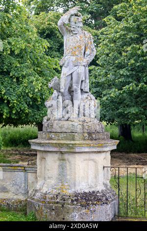 Sculpture en pierre d'un chasseur avec des chiens dans les jardins du Somerleyton Hall, Suffolk, Royaume-Uni, le 16 juin 2024 Banque D'Images