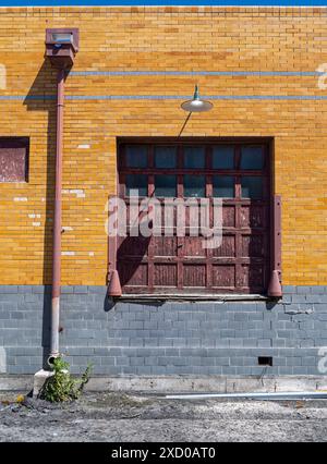 La peinture pelable sur la porte d'un quai de chargement d'un dépôt de train avec un mur de briques vitrées Banque D'Images