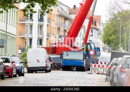 Grue à flèche mobile de charge extra-lourde travaillant sur un arrière-plan étroit de la vieille ville européenne. Chantier de construction de l'équipement de levage de la flèche télescopique Banque D'Images