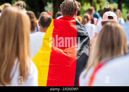 Fußballfans auf dem Weg zur Fan zone im Olympiapark, in Deutschlandfahne gehüllt, Fußball-EM, München, 19. Juni 2024 Deutschland, München, 19. Juni 2024, Fußballfans mit Deutschlandfahne auf dem Weg zur Fan zone im Olympiapark, vor dem Spiel Deutschland-Ungarn, public Viewing in der Fan zone im Olympiapark, Sommermärchen, Fußball-EM, UEFA EURO 2024, Fußball-Europameisterschaft, Fußball, Sport, *** fans de football sur le chemin de la zone des fans dans le parc olympique, enveloppé dans le drapeau allemand, Championnat d'Europe de football, Munich, 19 juin 2024 Allemagne, Munich, 19 juin 2024, fans de football avec allemand Banque D'Images