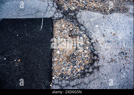 La section de la route qui vient d'être réparée obtient un nouveau nid de poule Banque D'Images