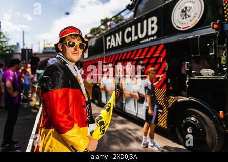 Stuttgart, Allemagne. 19 juin 2024. Football, Championnat d'Europe, marche des fans, visionnement public Allemagne - Hongrie. Un fan allemand enveloppé de noir, rouge et or se tient à côté du bus du fan club de la Fédération allemande de football (DFB) pendant la marche des fans. Crédit : Philipp von Ditfurth/dpa/Alamy Live News Banque D'Images