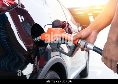 Ravitaillement de la voiture à une station d'essence pompe à essence. L'homme de main du conducteur et le remplissage de l'huile d'essence de pompage la voiture avec le plein de carburant à il. Ravitaillement en vol de voiture Banque D'Images