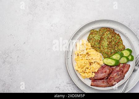 Photographie de nourriture vierge du petit déjeuner, oeuf brouillé avec bacon et crêpe de courgette, frit ; croustillant ; courgettes ; concombre; assaisonnement ; brunch Banque D'Images