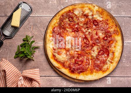 Photographie alimentaire de pizza avec salami épicé, piment rouge, pepperoni, mozzarella, fromage; porc, viande ; sauce tomate ; origan ; fond; repas ; nourriture Banque D'Images