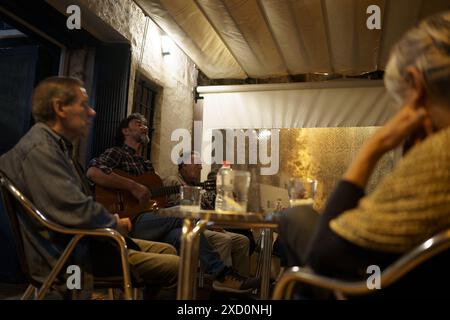 Es Castell, Espagne. 15 juin 2024. Un homme est vu chanter et jouer de la guitare pour les touristes et les habitants dans un bar dans le port de la ville. Plus de 90 millions de touristes devraient visiter l'Espagne en 2024, dont beaucoup se rendront aux îles Baléares, un nombre record, ce qui en fait le deuxième pays le plus visité au monde. (Photo de Davide Bonaldo/Sipa USA) crédit : Sipa USA/Alamy Live News Banque D'Images