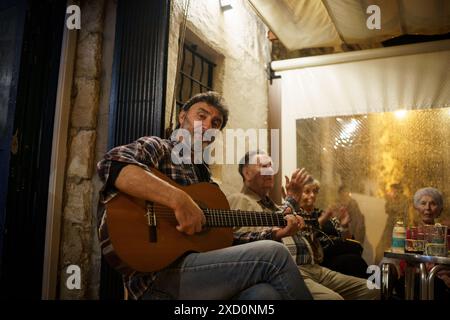 Es Castell, Espagne. 15 juin 2024. Un homme est vu chanter et jouer de la guitare pour les touristes et les habitants dans un bar dans le port de la ville. Plus de 90 millions de touristes devraient visiter l'Espagne en 2024, dont beaucoup se rendront aux îles Baléares, un nombre record, ce qui en fait le deuxième pays le plus visité au monde. (Photo de Davide Bonaldo/Sipa USA) crédit : Sipa USA/Alamy Live News Banque D'Images