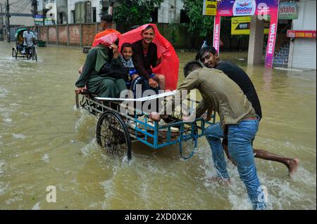 Sylhet, Bangladesh. 19 juin 2024. Sylhet, Bangladesh. Les résidents de la zone résidentielle d'élite de ​​Shahjal Upashahar de Sylhet se déplacent dans des pousse-pousse et des fourgonnettes de pousse-pousse sur des routes inondées. Alors que la situation des inondations s’aggrave dans la ville de Sylhet, de nombreuses personnes dans les zones résidentielles d’Upashahar quittent leurs maisons et déménagent vers des endroits plus sûrs. En raison des fortes pluies et des pentes montantes, des inondations ont eu lieu dans toutes les zones résidentielles le long des rives de la rivière de la ville de Sylhet. Crédit : majoritaire World CIC/Alamy Live News Banque D'Images