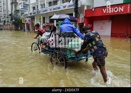 Sylhet, Bangladesh. 19 juin 2024. Sylhet, Bangladesh. Les résidents de la zone résidentielle d'élite de ​​Shahjal Upashahar de Sylhet se déplacent dans des pousse-pousse et des fourgonnettes de pousse-pousse sur des routes inondées. Alors que la situation des inondations s’aggrave dans la ville de Sylhet, de nombreuses personnes dans les zones résidentielles d’Upashahar quittent leurs maisons et déménagent vers des endroits plus sûrs. En raison des fortes pluies et des pentes montantes, des inondations ont eu lieu dans toutes les zones résidentielles le long des rives de la rivière de la ville de Sylhet. Crédit : majoritaire World CIC/Alamy Live News Banque D'Images