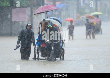 Sylhet, Bangladesh. 19 juin 2024. Sylhet, Bangladesh. Les résidents de la zone résidentielle d'élite de ​​Shahjal Upashahar de Sylhet se déplacent dans des pousse-pousse et des fourgonnettes de pousse-pousse sur des routes inondées. Alors que la situation des inondations s’aggrave dans la ville de Sylhet, de nombreuses personnes dans les zones résidentielles d’Upashahar quittent leurs maisons et déménagent vers des endroits plus sûrs. En raison des fortes pluies et des pentes montantes, des inondations ont eu lieu dans toutes les zones résidentielles le long des rives de la rivière de la ville de Sylhet. Crédit : majoritaire World CIC/Alamy Live News Banque D'Images