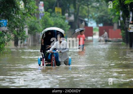 Sylhet, Bangladesh. 19 juin 2024. Sylhet, Bangladesh. Les résidents de la zone résidentielle d'élite de ​​Shahjal Upashahar de Sylhet se déplacent dans des pousse-pousse et des fourgonnettes de pousse-pousse sur des routes inondées. Alors que la situation des inondations s’aggrave dans la ville de Sylhet, de nombreuses personnes dans les zones résidentielles d’Upashahar quittent leurs maisons et déménagent vers des endroits plus sûrs. En raison des fortes pluies et des pentes montantes, des inondations ont eu lieu dans toutes les zones résidentielles le long des rives de la rivière de la ville de Sylhet. Crédit : majoritaire World CIC/Alamy Live News Banque D'Images