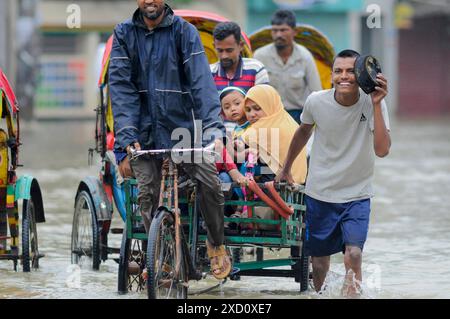 Sylhet, Bangladesh. 19 juin 2024. Sylhet, Bangladesh. Les résidents de la zone résidentielle d'élite de ​​Shahjal Upashahar de Sylhet se déplacent dans des pousse-pousse et des fourgonnettes de pousse-pousse sur des routes inondées. Alors que la situation des inondations s’aggrave dans la ville de Sylhet, de nombreuses personnes dans les zones résidentielles d’Upashahar quittent leurs maisons et déménagent vers des endroits plus sûrs. En raison des fortes pluies et des pentes montantes, des inondations ont eu lieu dans toutes les zones résidentielles le long des rives de la rivière de la ville de Sylhet. Crédit : majoritaire World CIC/Alamy Live News Banque D'Images